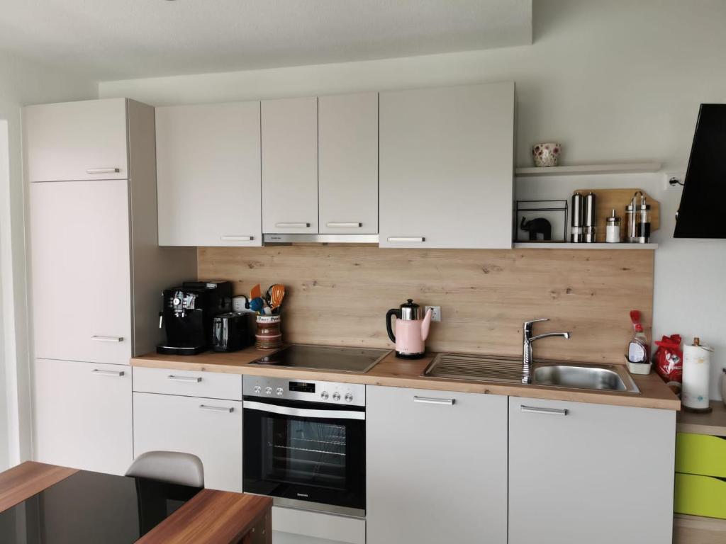 a white kitchen with white cabinets and a sink at Zeitlos Bodensee in Friedrichshafen