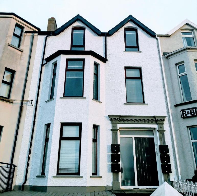 a white house with black windows on a street at Portrush by the Sea - 6 Golf Terrace in Portrush