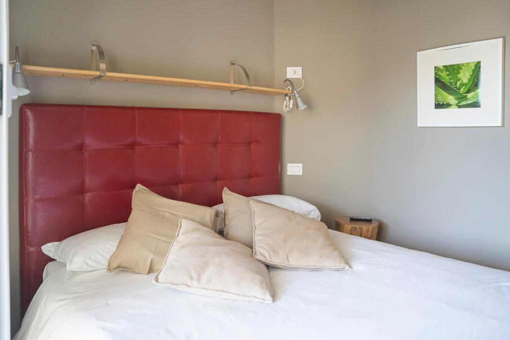 Bett mit rotem Kopfteil und weißen Kissen in der Unterkunft ALOE - Villa Luisa: Pace e Relax a 2 passi dal mare in Casarza Ligure