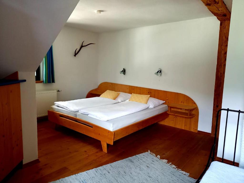 una camera con letto in legno e lenzuola bianche di Ferienwohnungen Alpenblick Vierbauch a Flattach