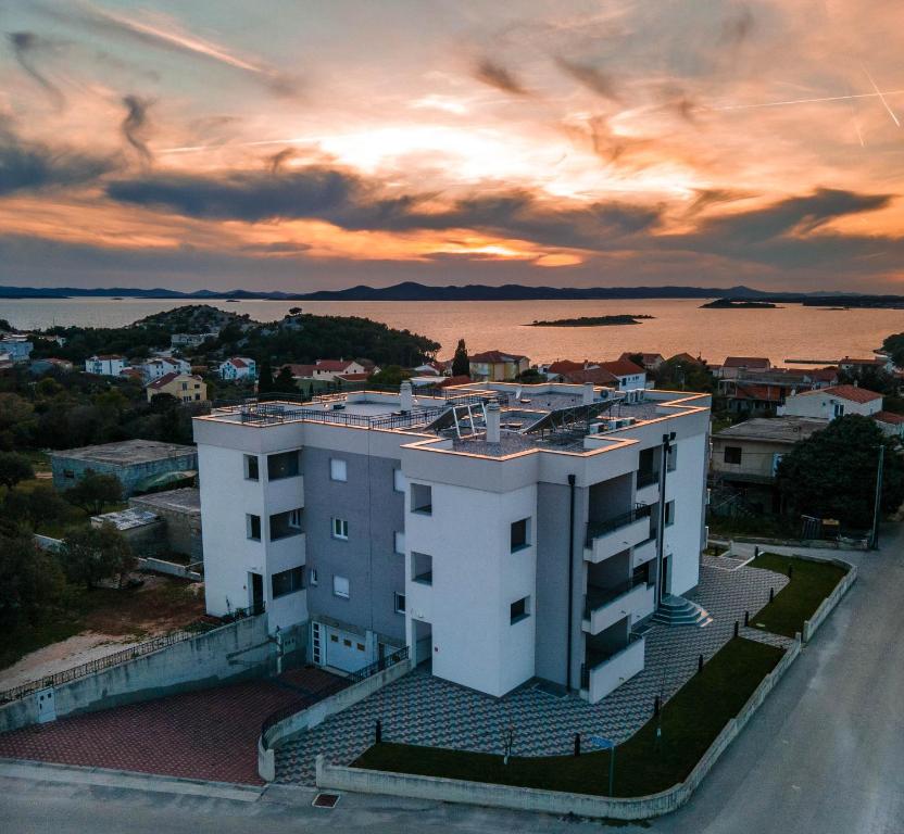 德拉葛的住宿－Apartmani Dalmacija Drage，白色的建筑,背面有日落