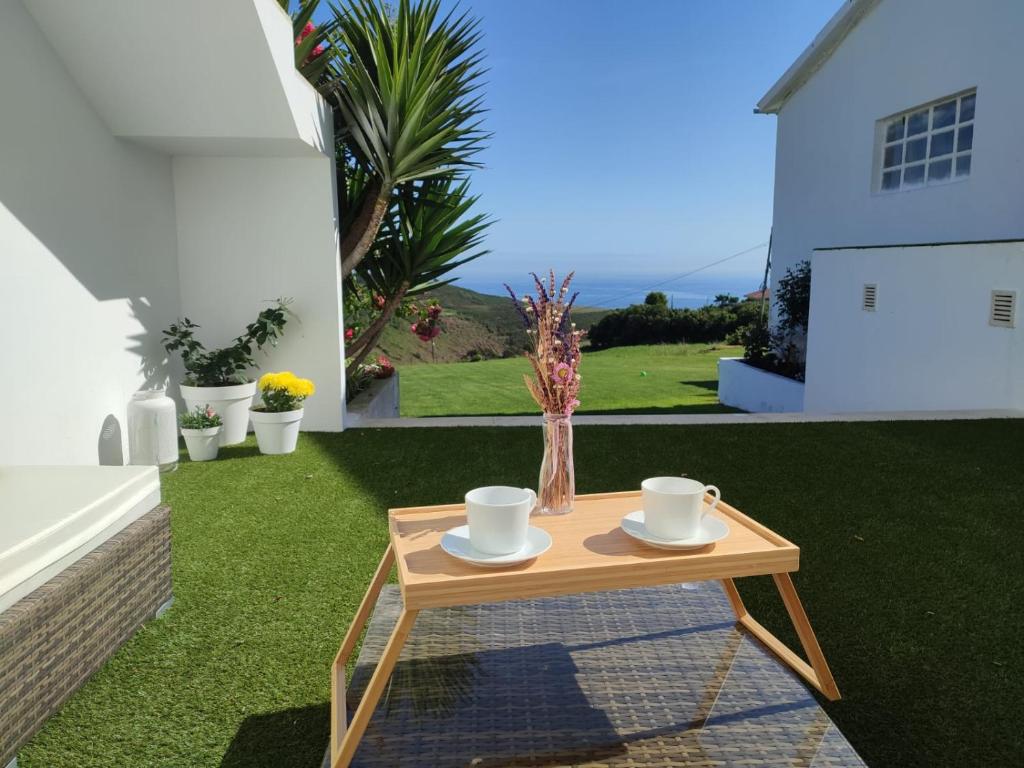 a wooden table with cups and saucers on a lawn at Tu Casina del Norte in Luanco