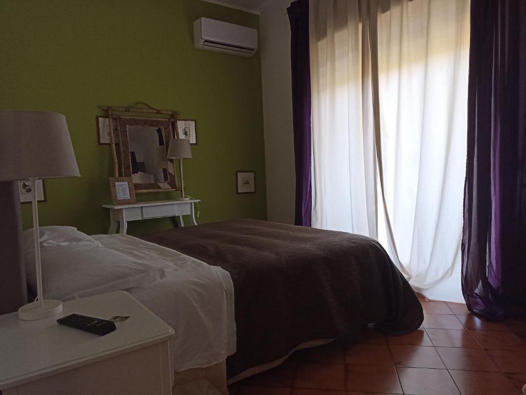 um quarto com uma cama, um espelho e uma janela em Massalargia em Mascalucia