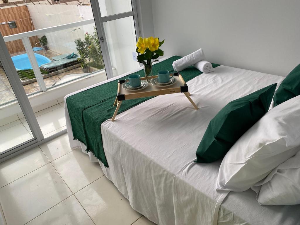Una cama con una mesa con un jarrón de flores. en Temporada 737, en Aracaju