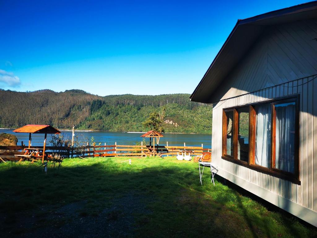 a house with a view of a lake and a picnic table at Camping & Cabaña Los Arrayanes Niebla in Valdivia