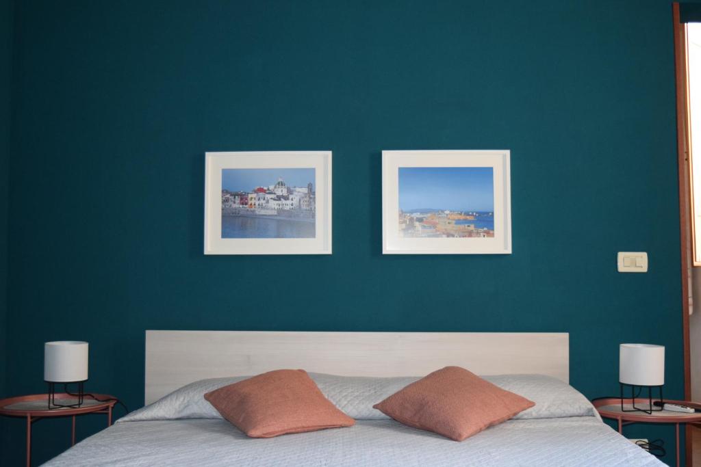 ein Schlafzimmer mit zwei Bildern an einer blauen Wand und einem Bett in der Unterkunft VESPRI 15 apartments in Trapani