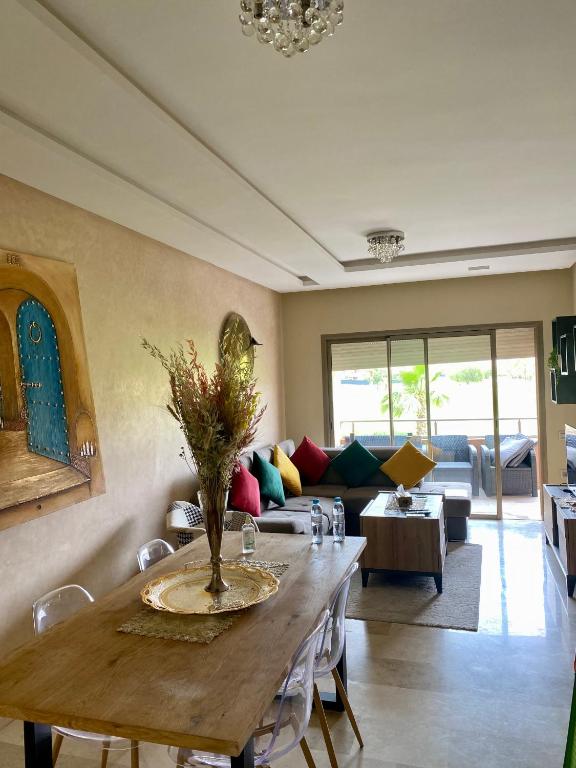 a living room with a table and a couch at Comme a la maison Prestigia Golf acces piscine in Marrakesh