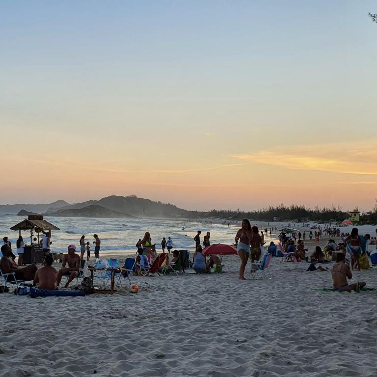 a group of people on the beach at sunset at Surf a poucos passos do mar, casa com lareira in Garopaba