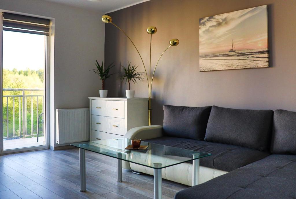 uma sala de estar com um sofá e uma mesa de vidro em Apartment 50m2 with a large living room, bedroom, balcony and free private parking em Gdansk