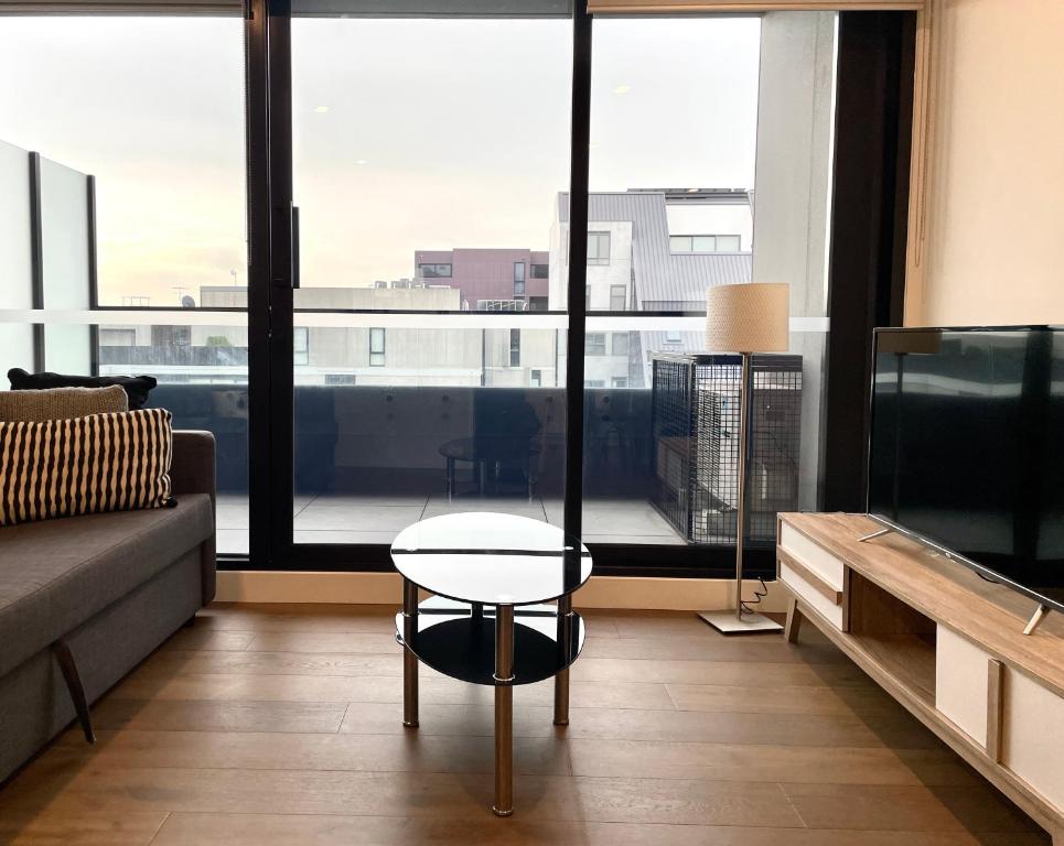 a living room with a table and a large window at Readyset Apartments at Marque in Melbourne