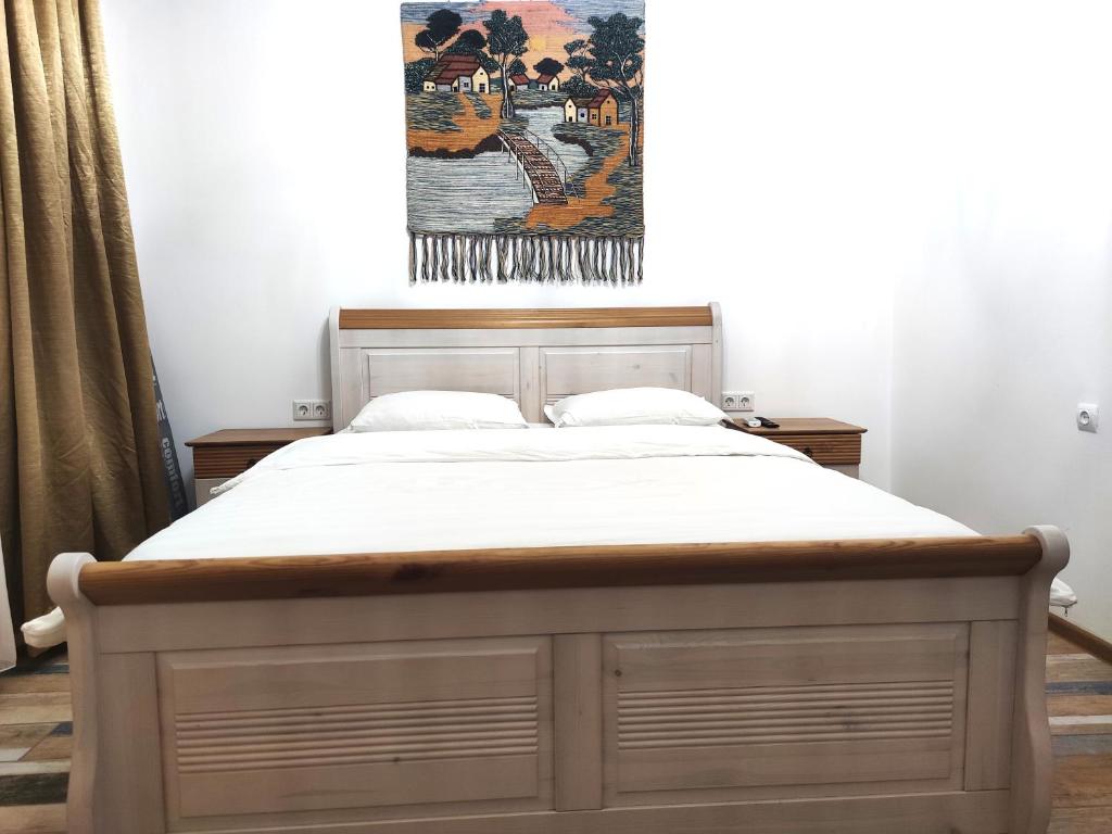 a bed in a bedroom with a painting on the wall at Loftik Apartments Gagarin street in Almaty