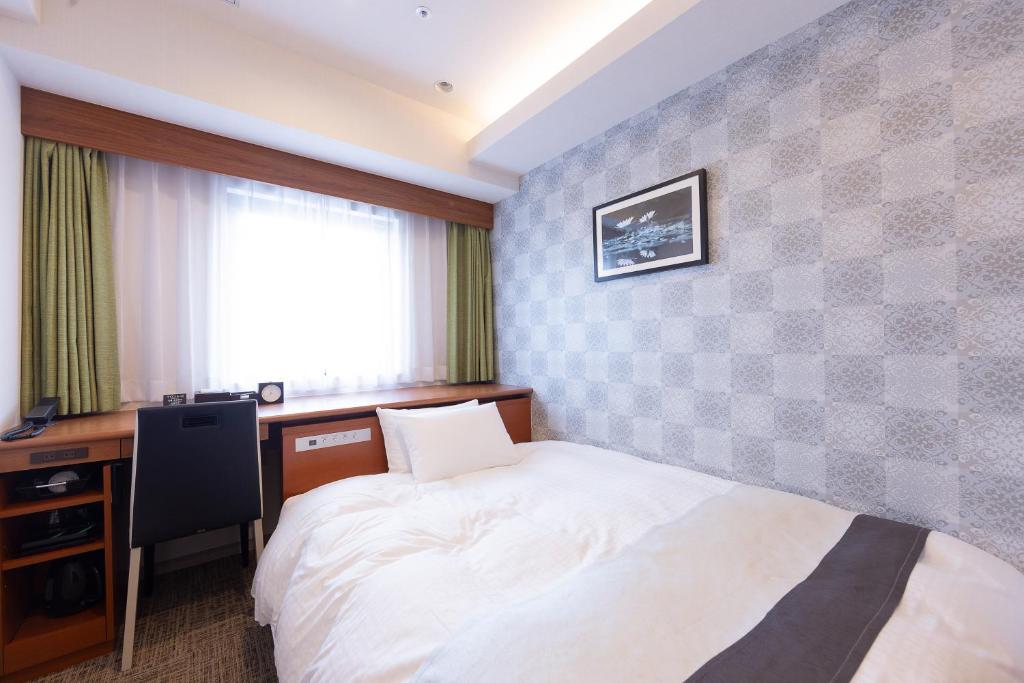 a bedroom with a bed and a desk and a window at Hotel Actel Nagoya Nishiki in Nagoya