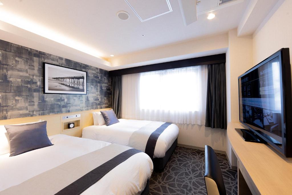 a hotel room with two beds and a flat screen tv at Hotel Actel Nagoya Nishiki in Nagoya