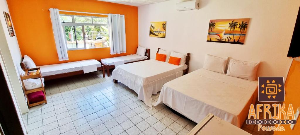 a room with two beds and a window at Pousada Afrika in Porto De Galinhas