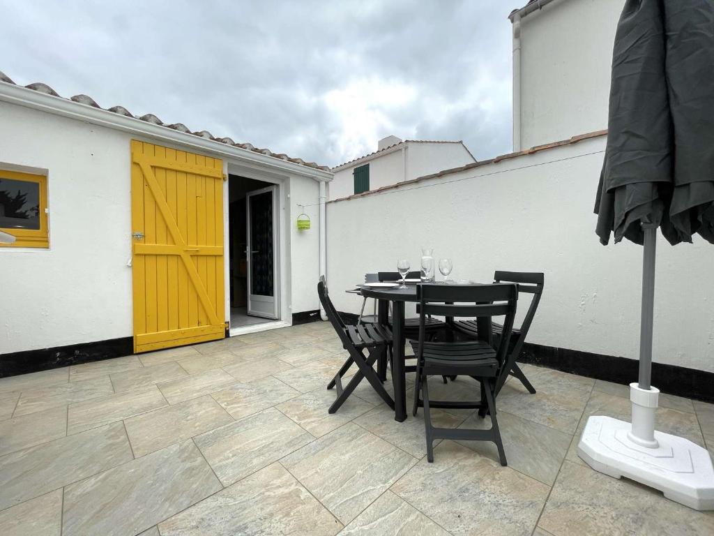 d'une terrasse avec une table et des chaises ainsi qu'une porte jaune. dans l'établissement Petite maison rénovée près de la mer avec piscine chauffée, tennis et patio - Bretignolles-sur-Mer - FR-1-224A-55, à Bretignolles-sur-Mer