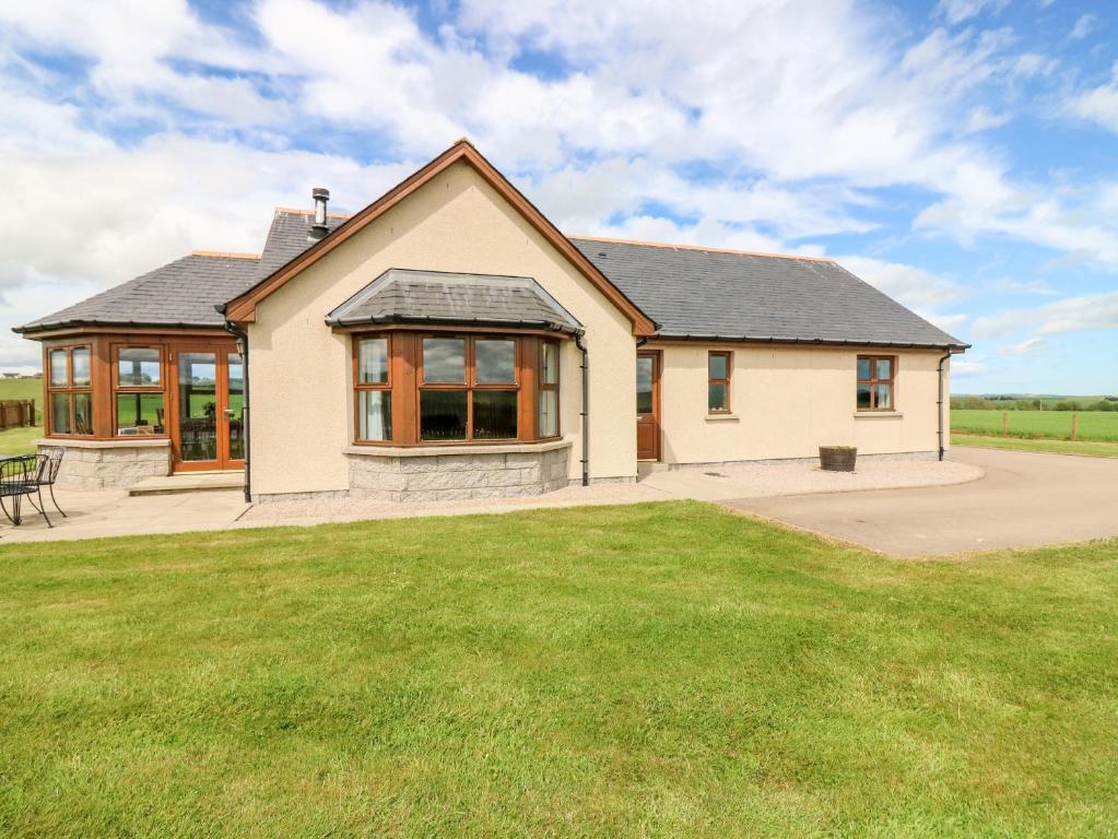 une maison avec une pelouse devant elle dans l'établissement Kilnary Cottage, à Ellon