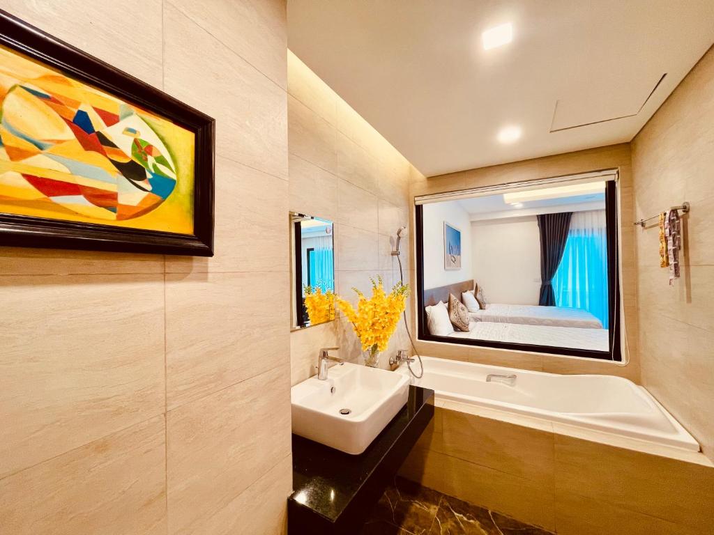 クイニョンにあるFLC SEA TOWER - 4 SEASONS Apartmentの洗面台と鏡とベッドのあるバスルーム