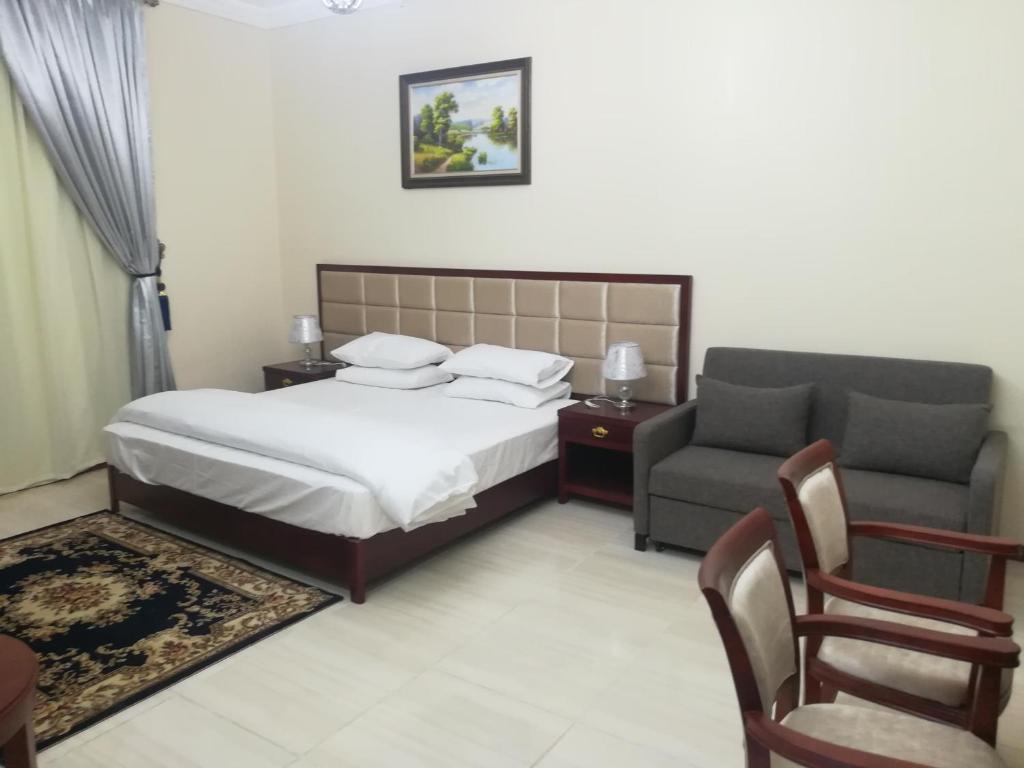 ein Schlafzimmer mit einem Bett, einem Sofa und einem Stuhl in der Unterkunft نسيم الفجر للشقق المخدومة in Dschidda