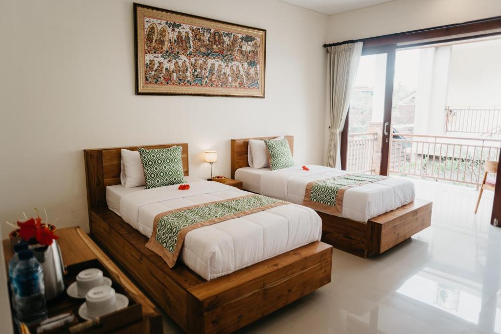 a bedroom with two beds and a balcony at Tu Sandat Homestay in Ubud