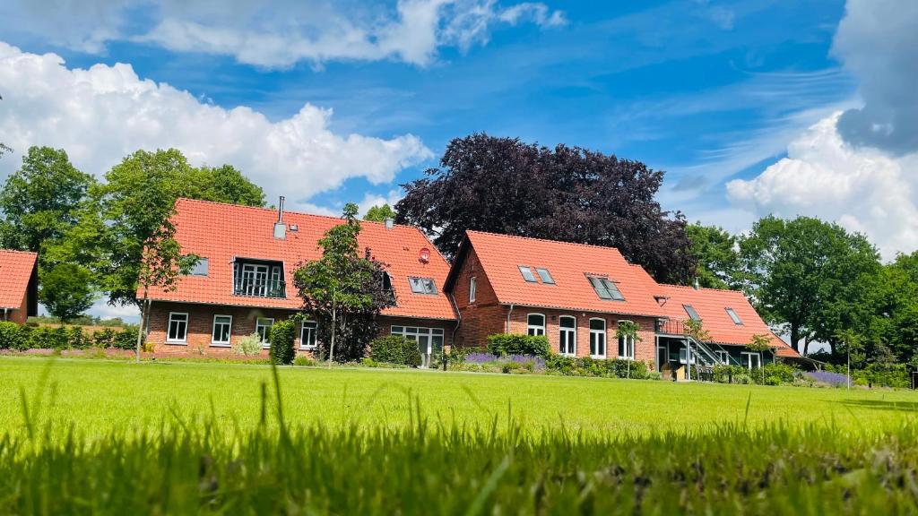 a row of houses with orange roofs on a green field at Meine Schule Sehlingen, stilvolle Familien-Unterkunft auf dem Land in Kirchlinteln
