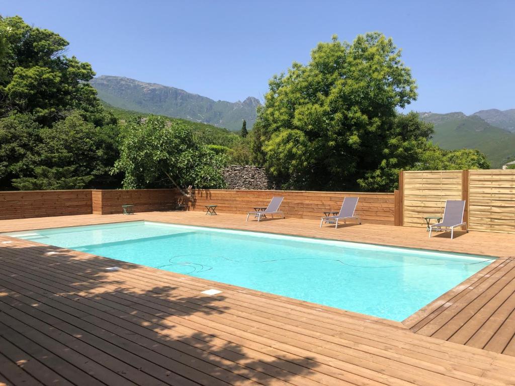 una piscina con 2 sillas y una terraza de madera en Le Relais de Sisco, en Sisco