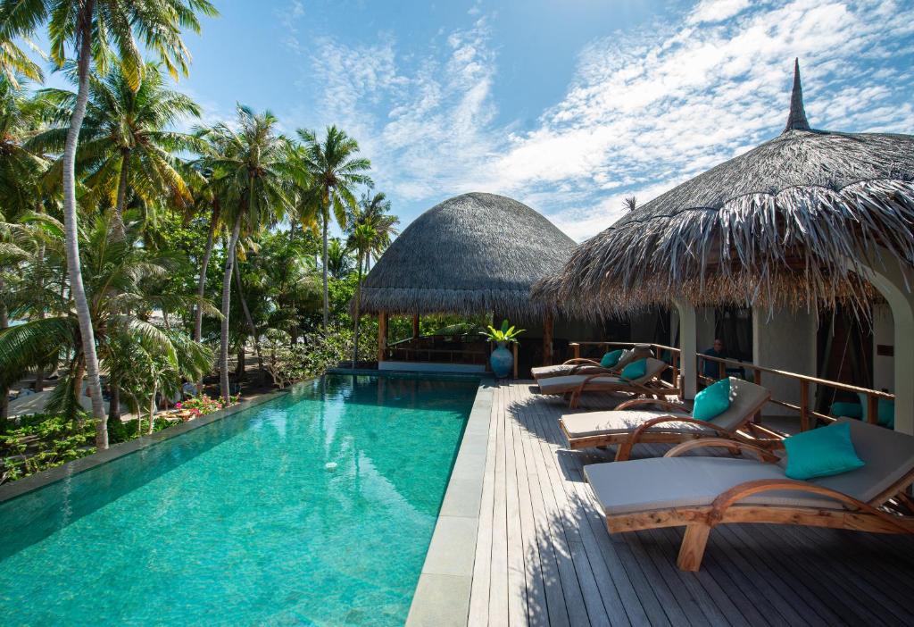 福拉杜島的住宿－Island Luxury Boutique Hotel - Fulhadhoo，毗邻度假酒店的带椅子和遮阳伞的游泳池
