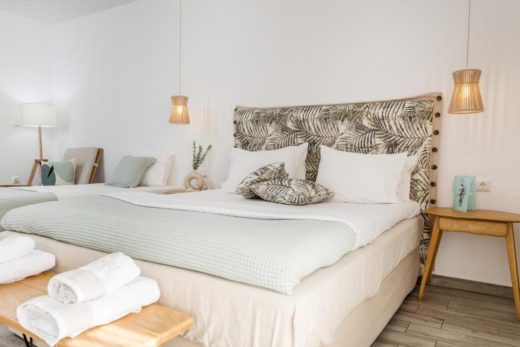 Korali Boutique Hotel في ناكسوس تشورا: غرفة نوم بسريرين مع شراشف ووسائد بيضاء