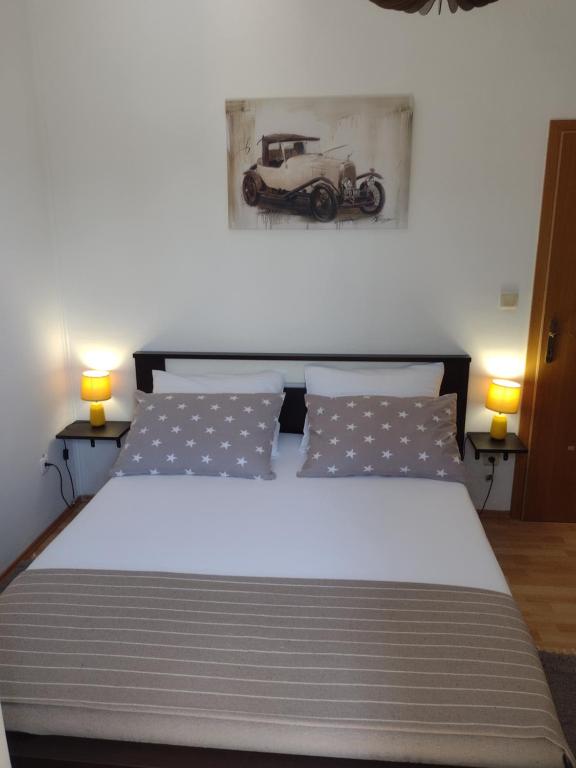 um quarto com uma grande cama branca e 2 candeeiros em Kalauz Rooms em Lozovac