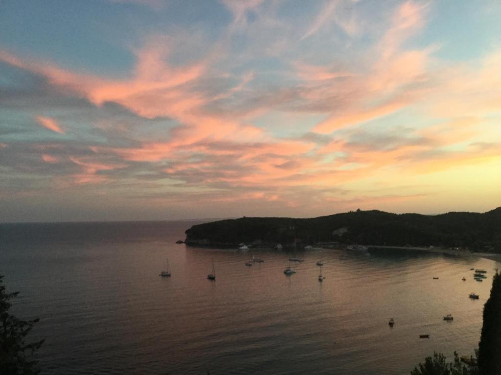 una puesta de sol sobre un cuerpo de agua con barcos en Palatino Hotel, en Parga