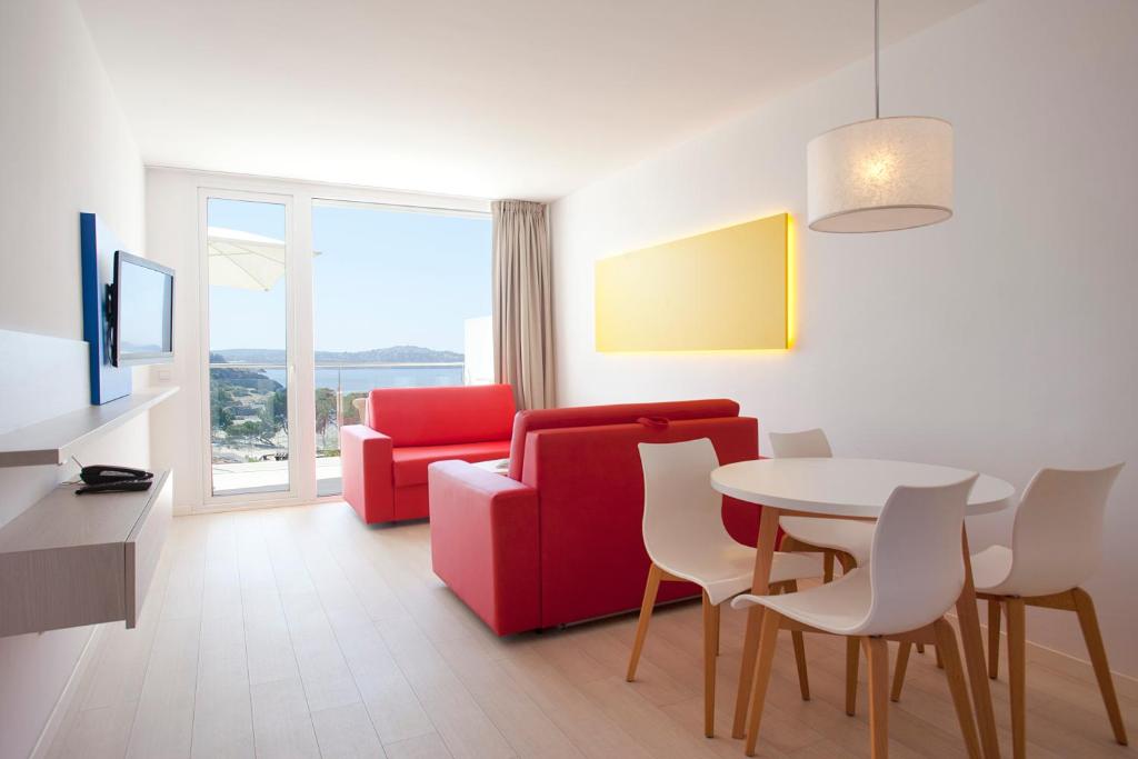 a living room with a red couch and a table at Aparthotel Novo Mar in Paguera
