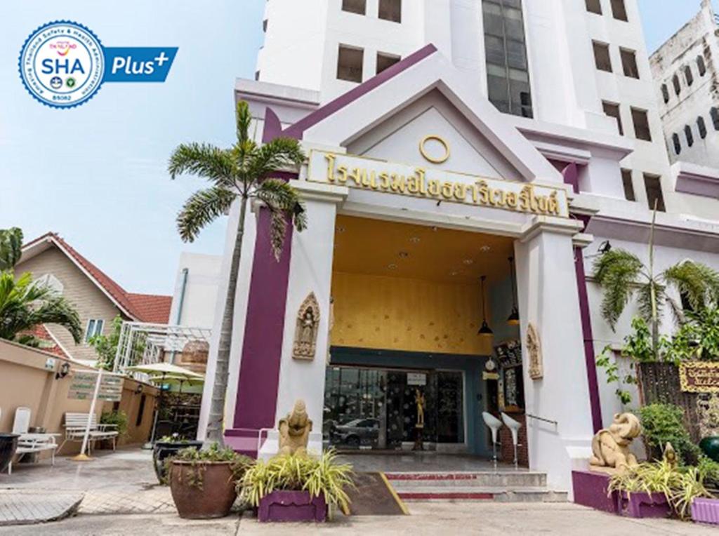 a store front of a building with a palm tree at Ayothaya Riverside Hotel in Phra Nakhon Si Ayutthaya