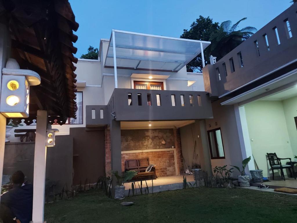 a house with a balcony with a fireplace at Villa Names2 Gunung Bunder in Gunungpicung