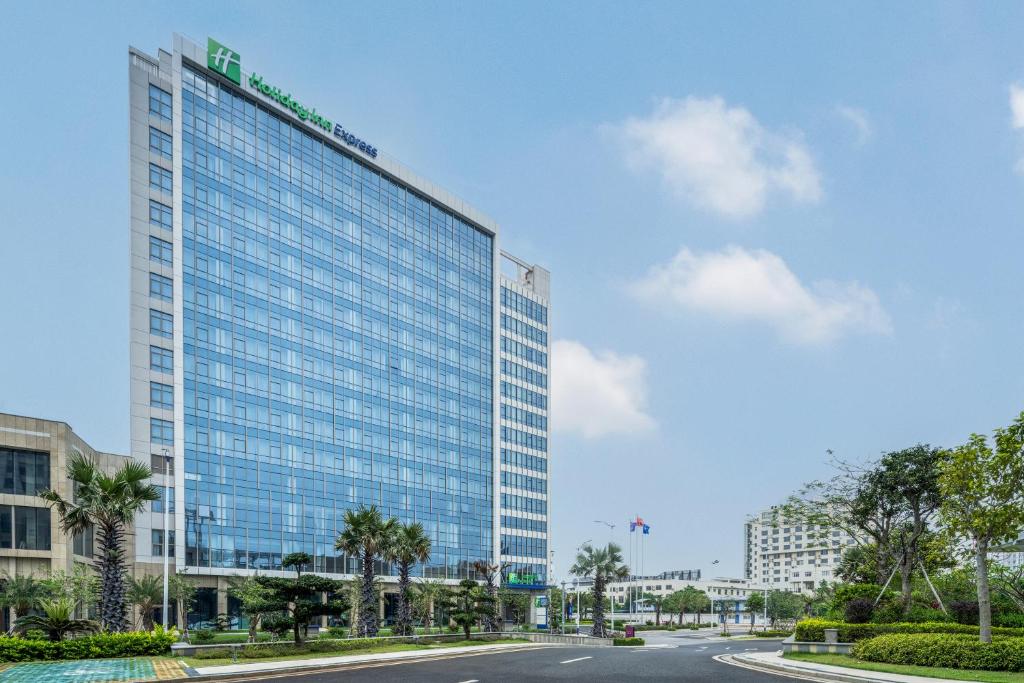 un grand bâtiment en verre avec une route devant lui dans l'établissement Holiday Inn Express Beihai Silver Beach, an IHG Hotel, à Beihai