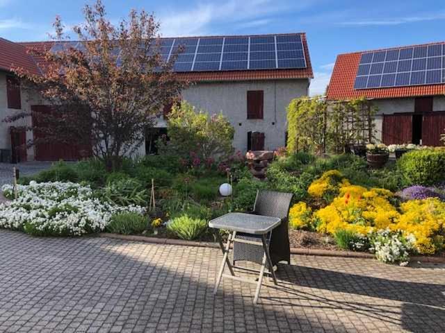 a table and a chair in a garden with solar panels at Ferienwohnung im Herzen von Thüringen in Blankenhain