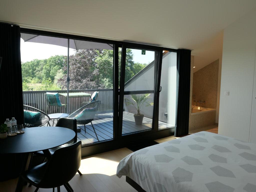 a bedroom with a bed and a balcony with a table and chairs at B&B De Stuifduinen in Wetteren