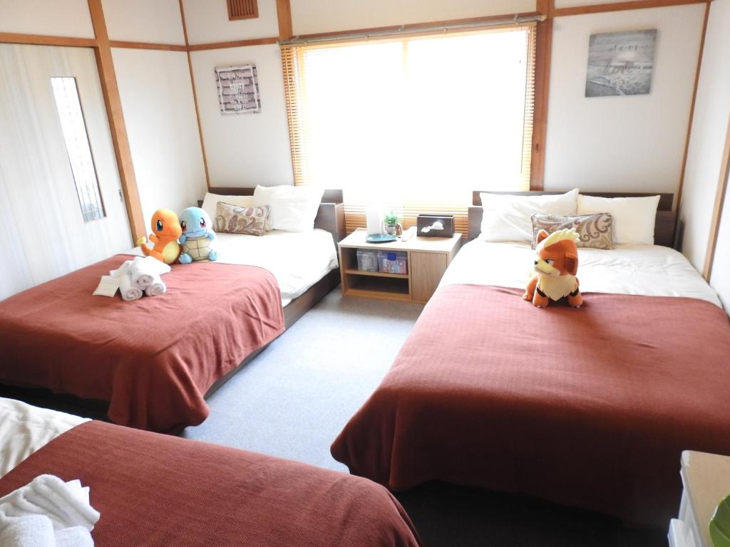 Zimmer mit 2 Betten mit ausgestopften Tieren in der Unterkunft 旭川貸切一軒家プラスティ in Asahikawa