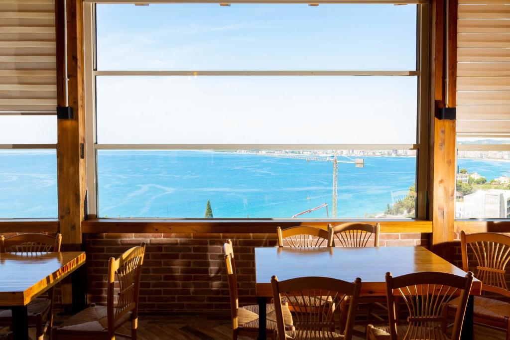 ein Restaurant mit Tischen und Stühlen und einem großen Fenster in der Unterkunft Aerial Hotel & Spa in Vlorë