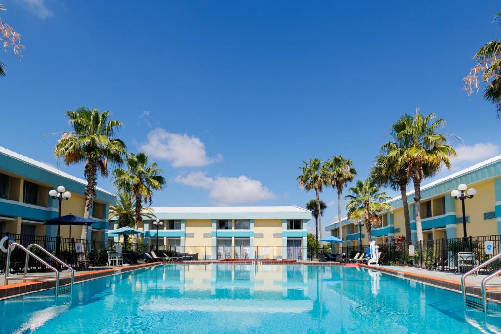 a large swimming pool in front of a hotel with palm trees at Garnet Inn & Suites, Orlando in Orlando