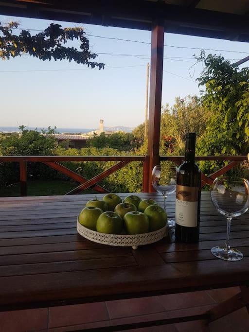 a table with a bowl of apples and a bottle of wine at Amalthia in Sitia