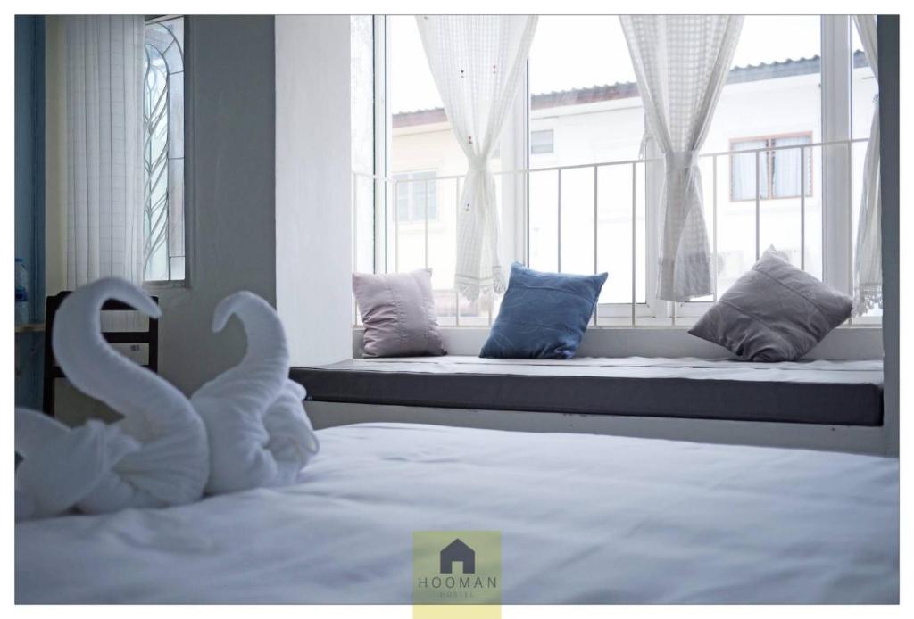 a bedroom with a bed with swans in front of a window at Hooman Hostel in Chiang Mai