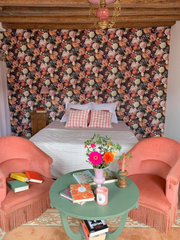 1 Schlafzimmer mit einem Bett, 2 Stühlen und einem Tisch in der Unterkunft Maison Léontine in Bernay