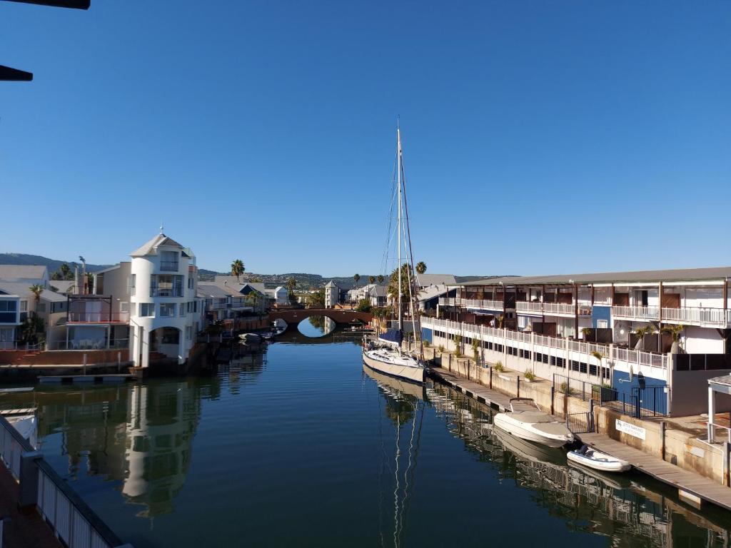 a group of boats docked in a river with buildings at Belle View @ Knysna Quays in Knysna