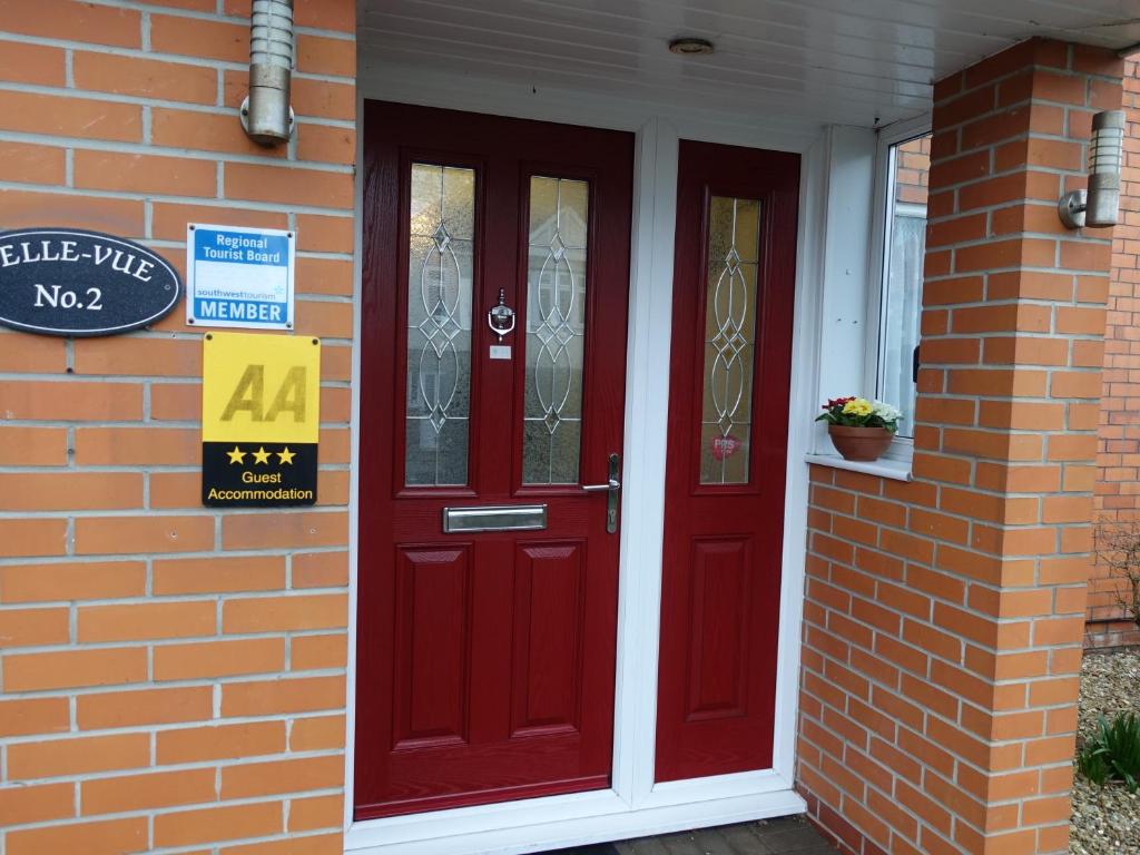 a pair of red doors on a brick house at Belle Vue Guesthouse in Glastonbury