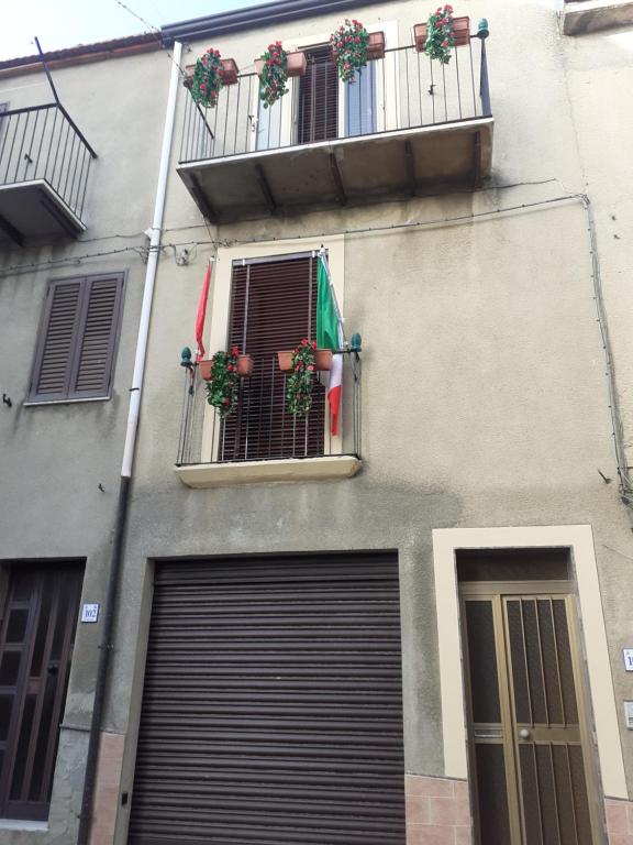 een gebouw met twee garagedeuren en een balkon met bloemen bij Affittacamere GERANI in Capizzi