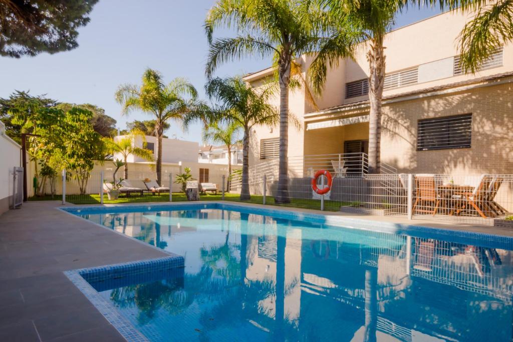 een zwembad voor een gebouw met palmbomen bij La Casa del Mar in Chiclana de la Frontera