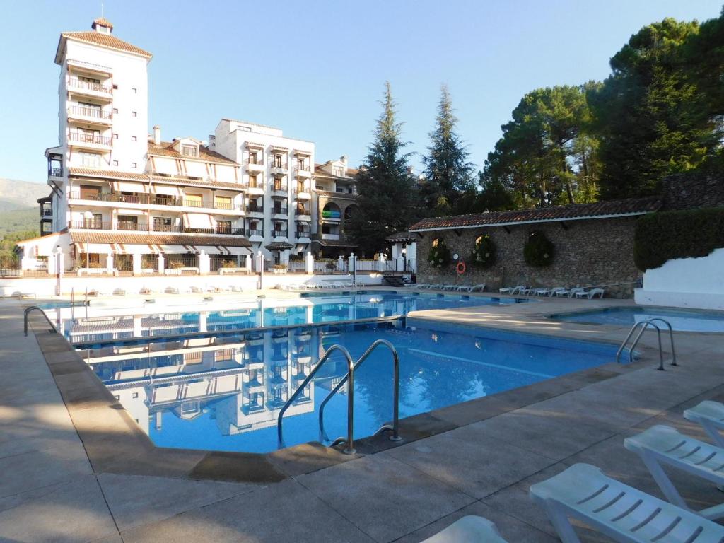a swimming pool with chairs in front of a building at El capricho para todos in Arenas de San Pedro