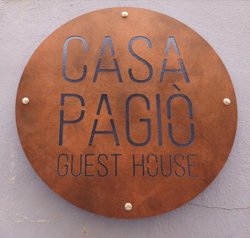 a sign for a casa paso guest house on a wall at Casa Pagiò in Bosa