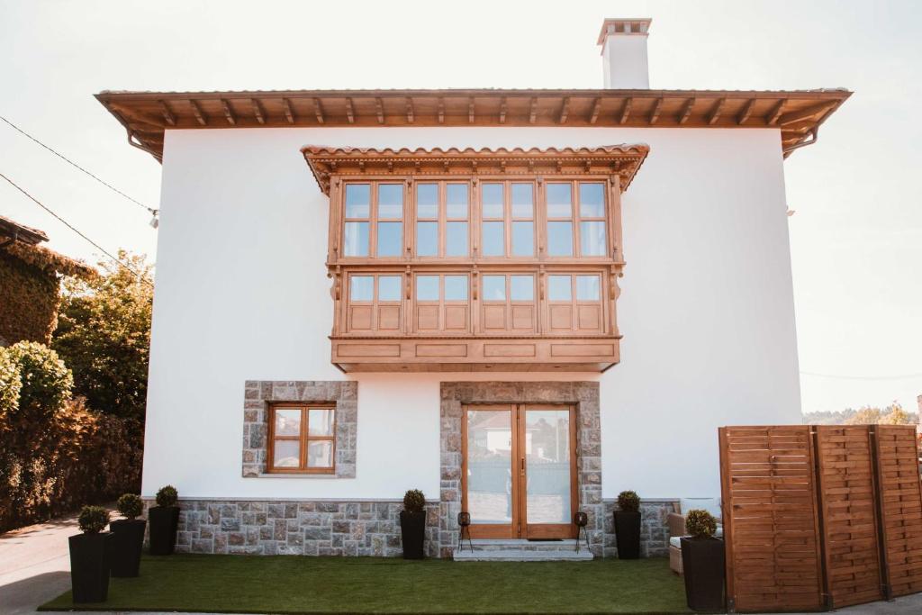 Casa blanca con puerta y ventanas de madera en El Riveru - Astur Casas Rurales, en Balmori