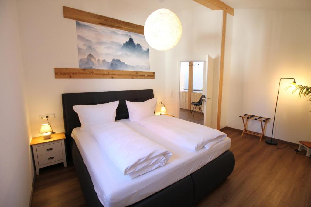 Allgäu Hütten Loft - Großzügig - Terrasse في Buchenberg: غرفة نوم بسرير كبير مع شراشف بيضاء