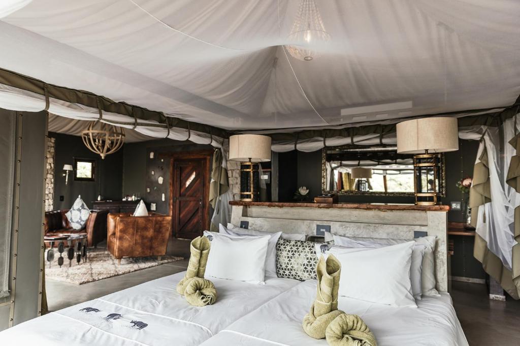 a bedroom with a large white bed with animal pillows at Etosha Oberland Lodge in Okaukuejo